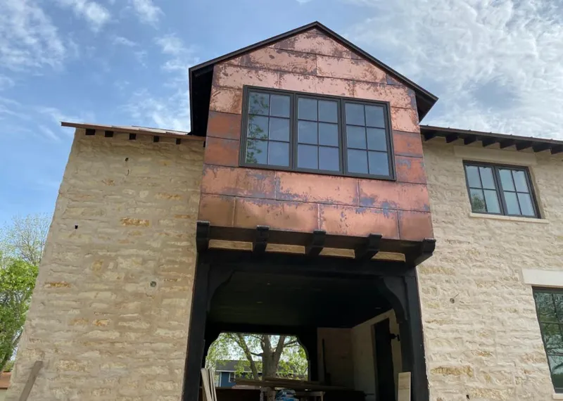 Copper metal panel facade on a stone building for Skylight Installation in Spirit Lake