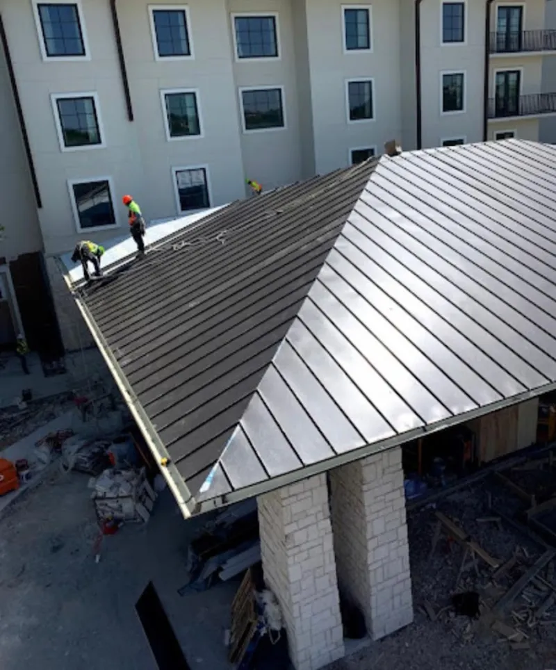 Crew installing standing seam metal roof panels on a commercial project in Spirit Lake